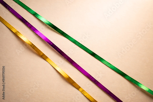 Vibrant Mardi Gras ribbons in purple, green and gold on beige background