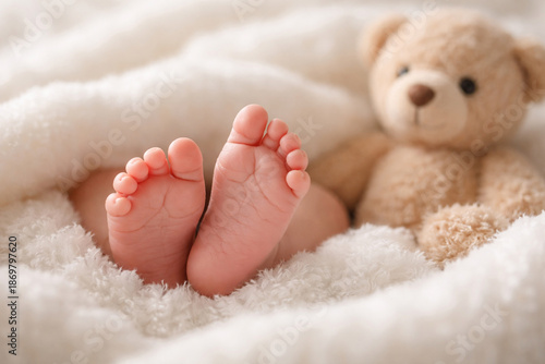 Baby feet peeking from a fluffy blanket with teddy bear in background — cozy nursery vibe