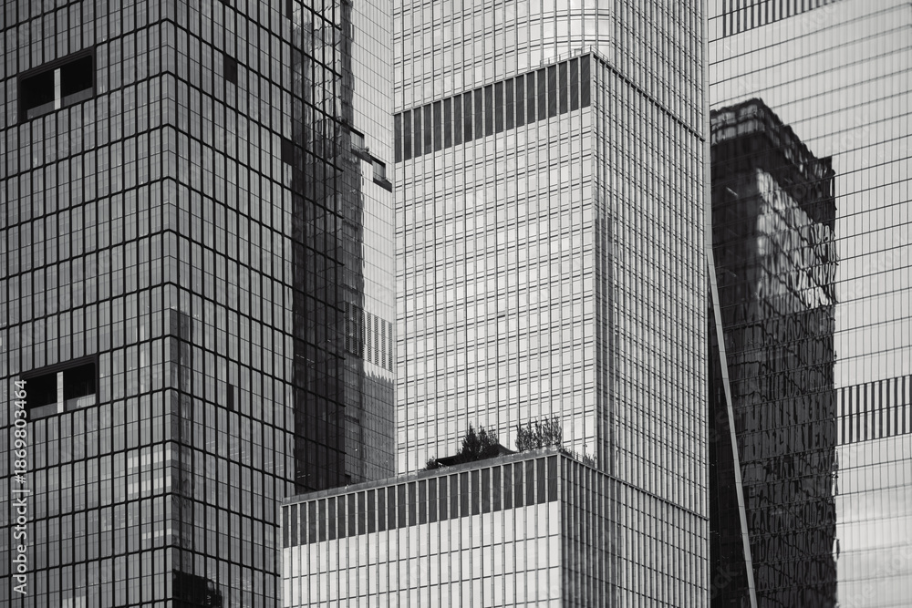 Fototapeta premium Low-angle view of modern skyscrapers in Manhattan, New York City. This dramatic perspective emphasizes the towering height and sleek design of the city's contemporary architecture. 