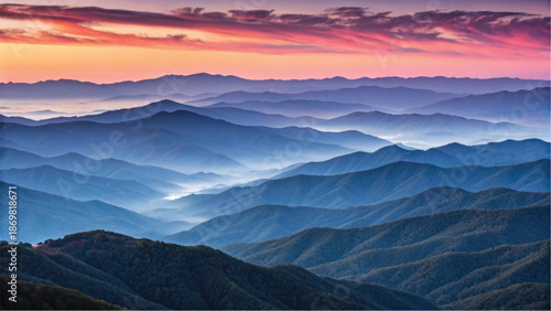 A breathtaking view of rolling blue mountains at dawn with colorful sky and mist-filled valleys