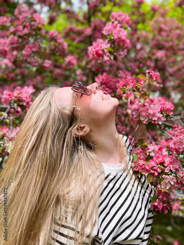 a young, beautiful girl with long hair is enjoying spring, flowers, and the fresh breeze
