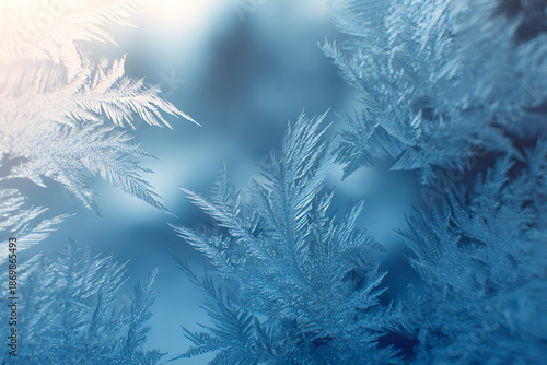 Szron na szybie w mroźny poranek, lodowe kryształy i zimowe wzory na niebieskim tle, delikatna tekstura natury.