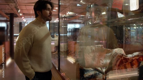 Meat assessment process, Inspecting meat in marketplace, Consumers scrutinize aged meat behind display, Evaluation of meat products by vendors and buyers occurs behind glass displays in markets