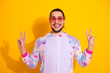 Happy young man in pastel pajama posing with peace sign for a playful lifestyle fashion photo