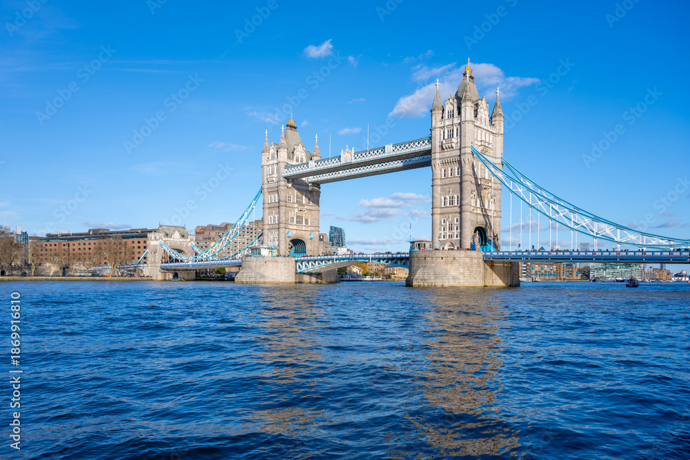 Obraz premium Tower Bridge stands majestically over the River Thames, showcasing its iconic structure against a clear blue sky. Visitors can admire the beauty of London from this historic landmark.