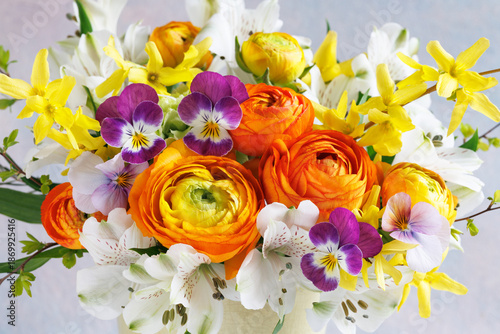 Beautiful bouquet of spring flowers close up, ranunculus, alstroemeria, pansies, forsythia. Card for spring holidays, Easter
