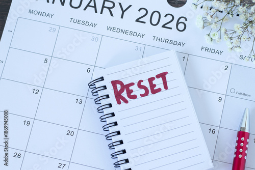 Reset handwritten word in notebook with January 2026 calendar. Top view. The concept of change, new beginning, progress, and time management.