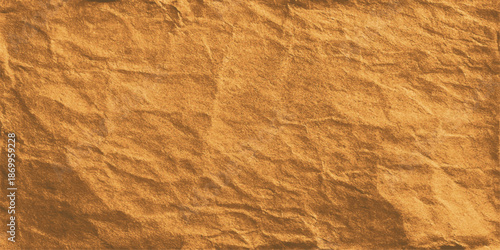 An aged and crumpled brown paper sheet features a rough sand texture background with a vintage grunge pattern on a wrinkled material surface for an antique design backdrop