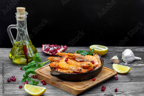 Fried shrimps with lemon, garlic and pomegranate on rustic wooden table