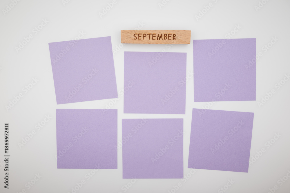 Fototapeta premium September planning concept with wooden block and purple sticky notes on white background. Monthly organization, task management, productivity, workflow and creative planning layout.