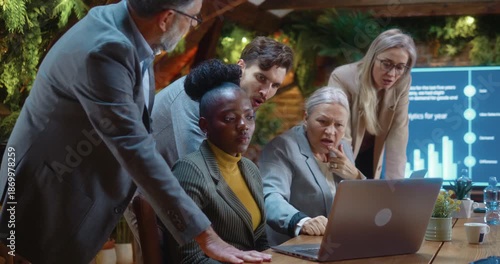 Business team looking at laptop and reacting negatively to bad news during corporate meeting, showing disappointment and concern after loss or market decline in modern eco-friendly office.
