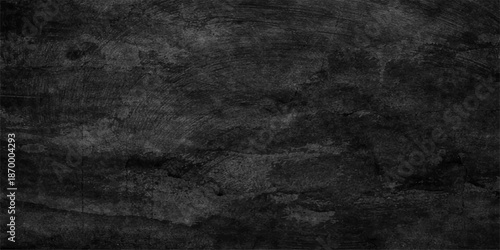 A dark grunge black and white texture of an aged concrete wall provides a vintage grey stone backdrop with a dirty textured surface for a blank design pattern