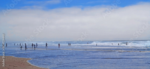 A panoramic view of people actively wading in the surf on a holiday weekend - Location: Pacific ocean beach front at Lincoln City, Oregon

