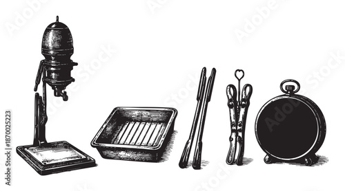 A black and white illustration of vintage photographic developing equipment including a timer, developing tray, tongs, and a timer, presented on a white background.