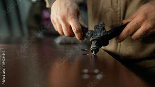 Worker hands using rivet gun joining metal parts
