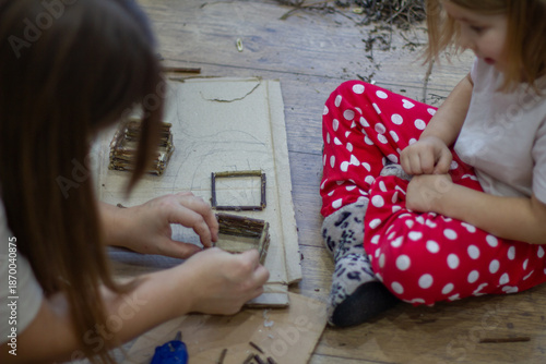 Mother and child creating a miniature house using twigs and natural materials, fostering creativity, education, and family bonding through diy craft activities.