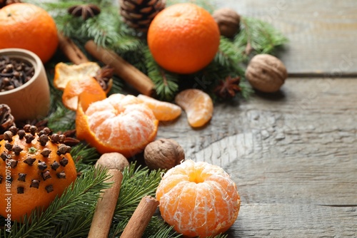 Foto Ripe tangerines, spices, walnuts, fir tree branches and cone on wooden table, closeup