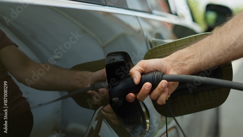 Εκτύπωση καμβά Close up of driver opening electric car charging port flap, attaching electric cable connector to recharge battery