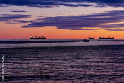sagome di navi da trasporto e barca a vela al tramonto viste dal lungomare di Salerno (Campania , Italia)