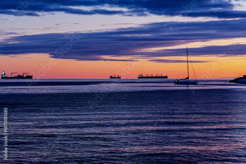 Sagome di navi da trasporto e barca a vela al tramonto viste dal lungomare di Salerno (Campania , Italia)