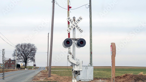 Obraz na plátně A rail crossing sign stands next to a rural road