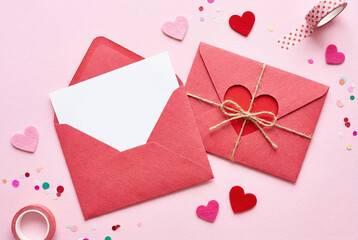 Valentine's day composition with red envelopes, hearts and confetti on pink background