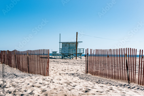 View through a sand fence towards a white lifeguard stand on the Californian coast