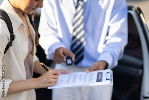 A female customer happily received the car keys from the salesperson after completing the car purchase, insurance, and loan paperwork, celebrating the successful completion of the car sale and 