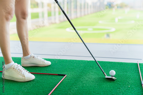 Close up of golfer preparing to hit golf ball on turf at driving range