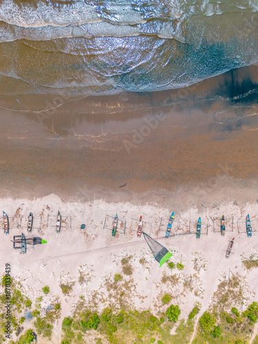 Aerial view from drone in bengkulu, indonesia showing turquoise indian waters, sandy beaches, small boats, and lush tropical hills.