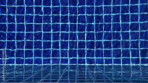 4K slow motion footage swimming pool with deep blue tiles. Sunlight creates shimmering ripples and soft waves across water surface perfect for tranquil backgrounds and summer themes