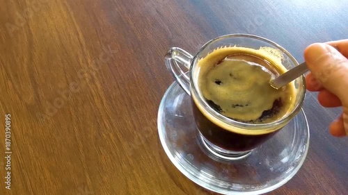 Glass cup of americano black coffee with spoon and plate.