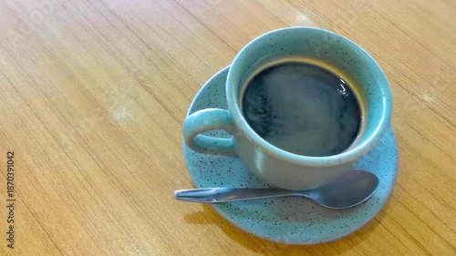 Blue cup of americano black coffee with spoon and plate.