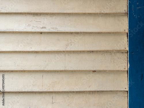 Close up of a white wooden painted timber walls  stacked horizontally with a blue painted column.
