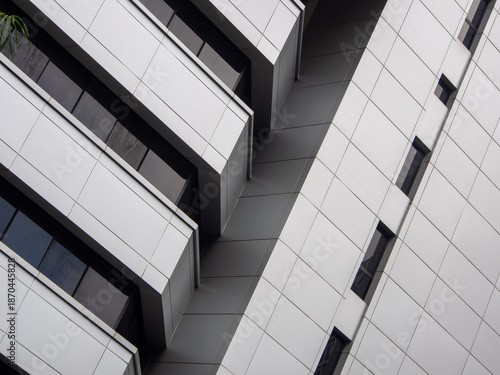 Grey exterior of a building with rectangular panels and glass windows.