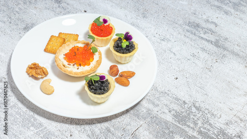 Assorted gourmet appetizers with caviar served on a plate with nuts and crackers