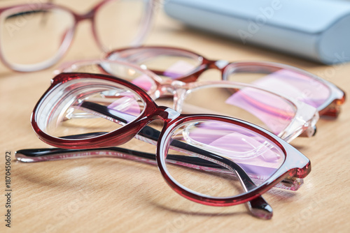 Multiple pairs of stylish red glasses for vision correction and eye care, with a blue case in the background.