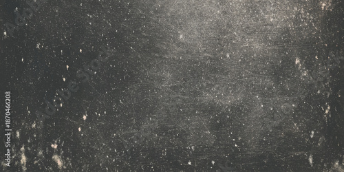 A grainy monochromatic image depicting a dark textured surface with scattered light specks and blurred patterns