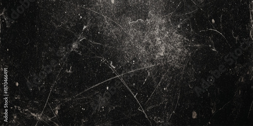 A dark textured background featuring a chaotic network of fine scratches and subtle dust particles