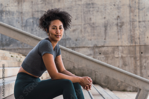 Fit young woman resting on concrete stairs, savoring a moment of calm post outdoor workout