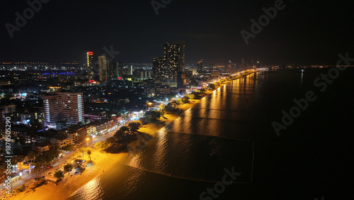 Breathtaking aerial view of pattaya city's illuminated skyline at night, showcasing the vibrant lights reflecting on the ocean and the bustling beach below