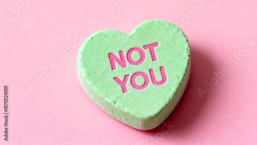 Light green heart-shaped candy with 'not you' message on a pink background