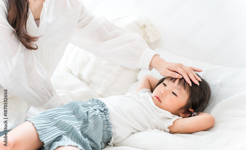 Fototapeta premium A mother places her hand on her child's forehead to check their temperature