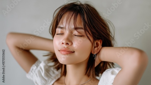 A lovely Filipina mestiza woman relaxes with her eyes closed and a gentle smile. She connects with a calming ambiance, expressing peace and contentment
