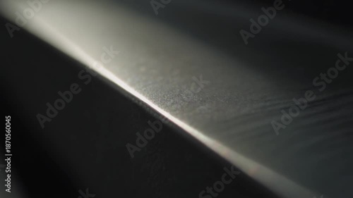 Close-up of a dark metallic surface with light reflection.