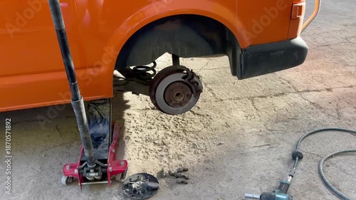 Orange van on a jack lift during wheel change at a service station