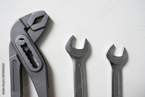 Wallpaper Mural Top view of an adjustable wrench, water pump pliers with red handles, and two combination spanners arranged on a white surface.  Torontodigital.ca