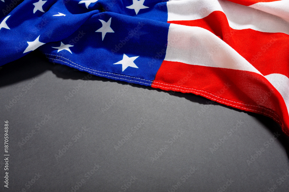 Fototapeta premium High angle shot of america flag with stars and stripes pattern on black table and copy space