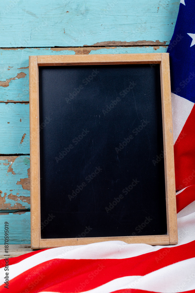 Fototapeta premium Overhead view of blank writing slate with copy space by usa flag on blue wooden table