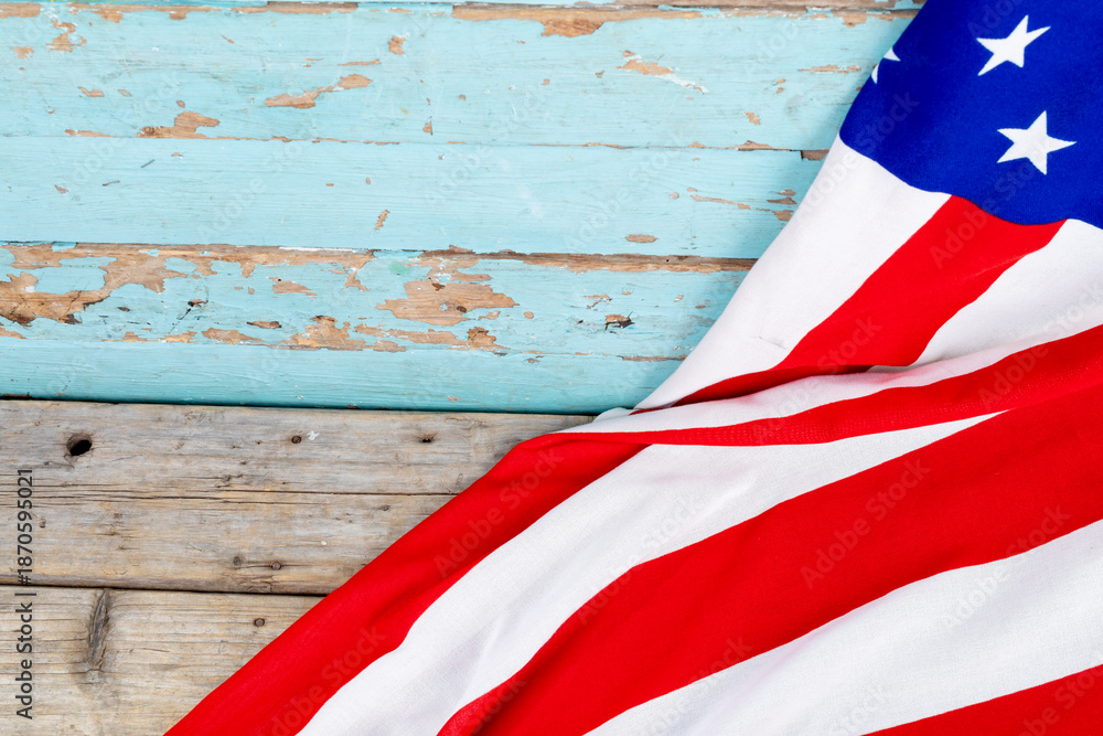 Fototapeta premium Red and white stripes with stars on usa flag over blue wooden table with copy space